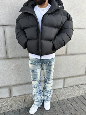 Svart pufferjacka från NVLTY - Säljer en svart pufferjacka från NVLTY med hög krage och vattenavvisande material. Jackan har en rejäl dragkedja framtill, breda quiltade sektioner och en loose passform som ger en cool och modern look. Perfekt för kalla dagar när du vill hålla stilen.