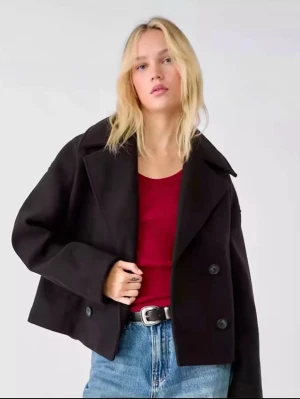  Stradivarius - Säljer en svart skepparkavaj från Stradivarius med dubbelknäppning och bred krage, är tillverkad i ett ullblandat material. Perfekt för dig som gillar en stilren och trendig look. Ganska nopprig. Pris kan diskuteras!