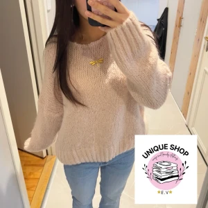 Ljusrosa stickad tröja - Mysig ljusrosa stickad tröja med oversized passform och långa ärmar. Tröjan har breda ribbade muddar vid ärmslut och nederkant, vilket ger en avslappnad look. Perfekt för lager på lager under kyliga dagar.