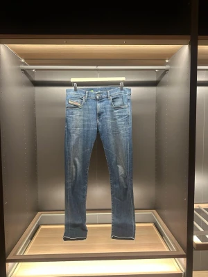 Diesel jeans - Säljer ett par blå Diesel D-Strukt jeans med slim passform och stretch. Klassisk femficksdesign, snygga slitningar och läderpatch med Diesel-logga bak i midjan. Perfekt för dig som gillar stilrena jeans med modern look. Storleken är W33 och L32. Hör av er vid frågor eller funderingar 