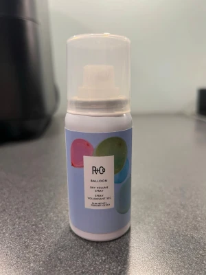 R+Co Balloon Dry Volume Spray - R+Co Balloon Dry Volume Spray i en smidig vit sprayflaska med blå etikett och färgglada ballonger. Ger volym och textur till håret, är vegansk och fri från parabener, sulfater och mineralolja. Innehåller 30 ml och har en praktisk plastkork. Helt oanvänd