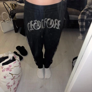 Svarta Mjukisbyxor Black Squad XS - Hej😊 säljer mina svarta mjukisbyxor från New Yorker, Black Squad, i storlek XS. Byxorna har snörning i midjan, ficka bak och silvriga detaljer med text och flames på framsidan och sidan.  Materialet är mjukt och skönt, har änvänt dom max 2 gånger. Hör av er vid frågor💕