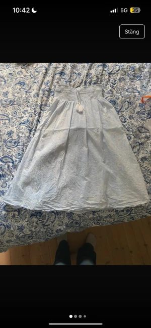 Ljusblå långkjol från Gina Tricot - Supersöt ljusblå långkjol från Gina Tricot med diskret paisleymönster. Kjolen har smock i midjan och dekorativa tofsar med knytband. Perfekt för sommarens alla dagar och riktigt skön att bära tack vare det tunna bomull soppsmaterialet.