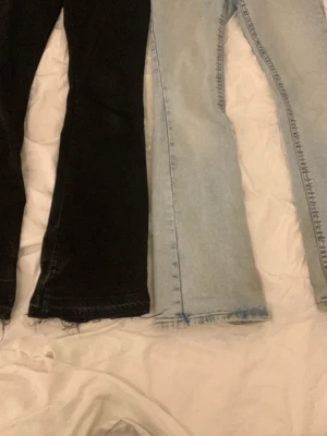 Bootcut jeans i svart och ljusblå - Två par jeans med bootcut-snitt, ett par i svart och ett par i ljusblå denim. Båda har råa, fransiga kanter vid bensluten och klassisk femficksdesign. Perfekta för dig som gillar en avslappnad och trendig stil. De är samma storlek och kan köpas tillsammans eller separat bara säg till. De svarta är nersprättade