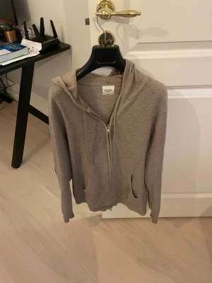 Beige hoodie med dragkedja från John Henric - Snygg beige hoodie från John Henric med dragkedja hela vägen, två fickor fram och skön huva. Jätte skön att ha på sig . Jag valde att sätta på två arm pads vid armbågen då det höll på att uppstå håll där. Fint skick finns några täcken på användning det finns ett litet hål vid armbågen med det syns endast ifall men lyfter armen  annars stans det inte alls.  annars jätte fin och skön tröja från John Henric .BYTEN KAN OCKSÅ VARA INTRESSANT. Bara att skriva vid frågor Med vänlig hälsning, 