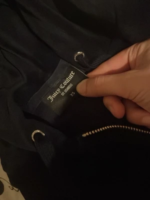 Svarta mjukisbyxor Juicy Couture XS -  Hela set för 600kr bara! Passa på att köpa. Svarta mjukisbyxor från Juicy Couture i storlek XS. Byxorna har guldfärgade detaljer på snörningen och fickor med guldfärgade knappar. Mjukt material och klassisk Juicy Couture-logga broderad på benet.