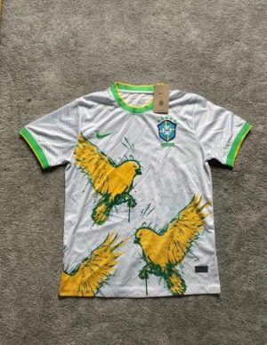 Vit Brasilien Nike fotbollströja M - Säljer en vit Brasilien fotbollströja från Nike i storlek M. Tröjan har gröna och gula detaljer vid krage och ärmslut, samt ett stort tryck med gula fåglar på framsidan. CBF-emblem på bröstet och Nike-logga. Materialet är lätt polyester med Dri-Fit teknologi.