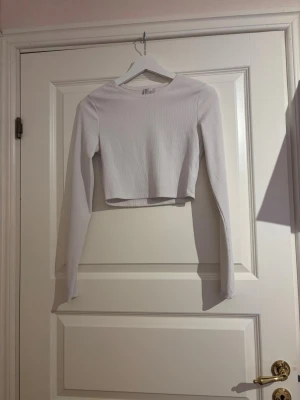Vit croppad långärmad topp H&M - En vit croppad långärmad topp från H&M.  Toppen är ribbad och är i storlek S. 