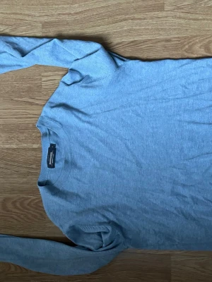 Ljusgrå långärmad tröja Dressmann - Säljer en stilren ljusgrå långärmad tröja från Dressmann i mjuk bomull. Tröjan har rund hals och enkel design som funkar till många olika outfits. Perfekt för dig som gillar basic och bekvämt.