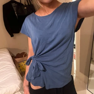 blå topp med knyt - blå topp från ONLY i storlek S. toppen har korta ärmar, rund hals och en knytning på sidan. materialet är väldigt mjukt💞