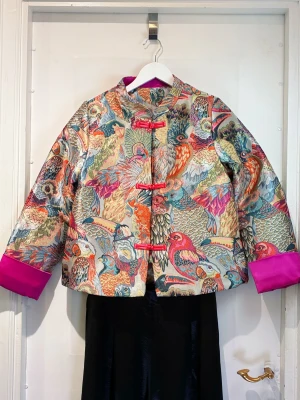 Broderad overshirt med fågelmönster - Vintage-style Artistic Silk Jacket   Beautiful 100% silk jacket with an artistic woven tropical rainforest pattern  Colorful, unique and very eye-catching – gives strong vintage + fashion editor vibes.  Brand new, never worn. Lightly padded, super comfortable and easy to style with jeans, trousers or skirts.  Measurements: • Bust: 104 cm • Length: 59 cm • Shoulder: 38 cm About European size 40 Open to offers for a quick sale 💌 