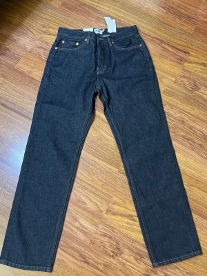 Mörkblå jeans Seattle från 157 - Säljer ett par mörkblå jeans från 157, modell Seattle. De har hög midja, raka ben och klassisk femficksdesign med kontrastsömmar. Materialet är slitstark bomullsdenim och passformen är normal. Perfekt för dig som gillar stilrena och tidlösa jeans.