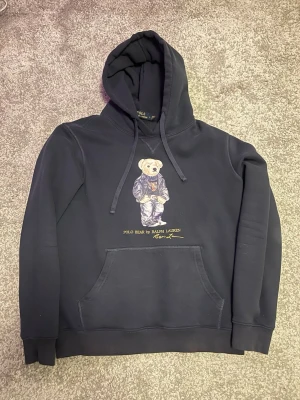 Polo bear Ralph Lauren Hoodie - Skön Ralph Lauren hoodie med björn design, storlek L/M, perfekt inför vintern och våren, om ni har några funderingar kan ni gärna höra av er, det finns ett hål vid handen men det är väldigt enkelt att fixa, priset är ej hugget i sten.