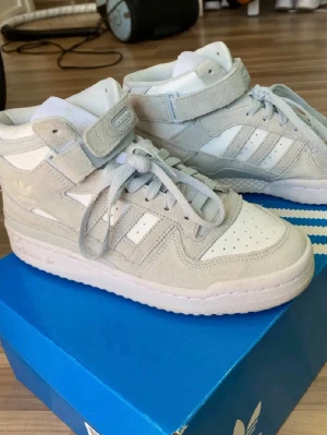 Adidas Forum Mid vita/grå sneakers - Säljer mina assnygga Adidas sneakers som jag aldrig använt. Storlek 38 :) 