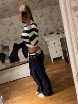 Randig croppad stickad tröja - Säljer en croppad stickad tröja med breda marinblå och vita ränder. Tröjan har lång ärm, rund halsringning och är ribbstickad för en snygg och bekväm passform i storlek s.