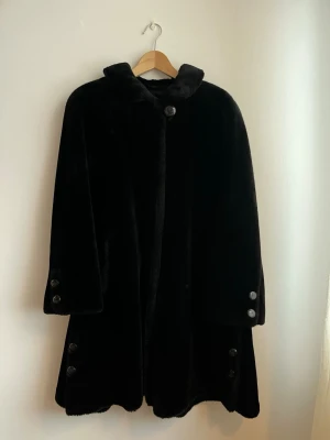 Svart kappa från Pierre Salomon, S-M. Vintage. - Fantastisk fin faux-fur kappa från Pierre Salomon. Köpt begagnad, ej använd av mig och den är i väldigt fint skick. Rymliga fickor och fina detaljer. Rejäl och varm.  Storlek 34 enligt tag, men skulle passa upp till 36/38.