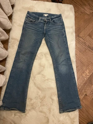 Blå bootcut jeans med broderad ficka. - Säljer ett par blå bootcut jeans med snygga broderade detaljer och knappar på bakfickorna. Jeansen har låg midja och klassisk femficksdesign. Materialet är jeans i bomull och de har en lätt tvättad look framtill och baktill. Från Gina tricot storlek 152