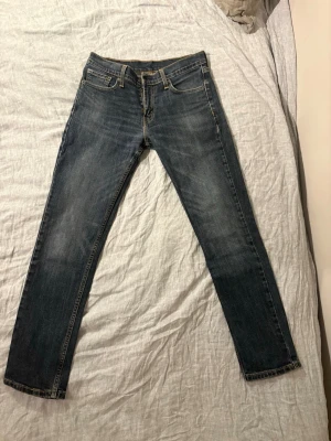 Levi's 511 blå jeans W30 L32 - Säljer ett par klassiska Levi's 511 jeans i blå tvätt. Modellen har normal passform med något smalare ben och fem fickor. Jeansen har snygga slitningar och kontrastsömmar. Perfekta till sneakers eller boots.