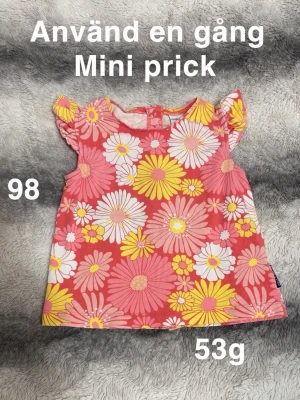 Blommig ärmlös t-shirt - Supergullig ärmlös t-shirt från Polarn o pyret i storlek 98. T-shirten har ett färgglatt blommönster i rosa, gult och vitt med volangdetaljer på axlarna. Perfekt för vår och sommar🌸 Använd en gång men fått en mini prick. Storlek 98 