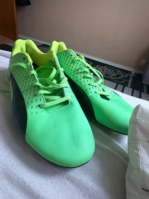 Gröna fotbollsskor från Puma - Säljer ett par riktigt snygga gröna fotbollsskor från Puma med svart detalj på sidan och gula dobbar.   Priset kan diskuteras.