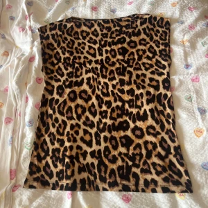 Leopardmönstrad topp från The Black Label - Säljer en snygg leopardmönstrad topp från The Black Label Collection. Toppen har klassisk rund halsringning och är ärmlös, perfekt för att sticka ut med ett djurmönster. Färgerna går i brunt, svart och beige och materialet känns mjukt och följsamt.