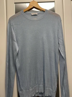 Ljusblå stickad tröja Tiger of Sweden - Säljer en stilren ljusblå stickad tröja från Tiger of Sweden i meronioull. Tröjan har rund halsringning, långa ärmar och är tillverkad i ett tunt, mjukt material som passar perfekt till både vår och höst. Enkel och clean design utan mönster eller detaljer.