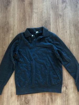 Arket pikétröja i bomull - Klassisk mörkgrå  långärmad pikétröja i mjuk 100% bomull. Tröjan har krage, två knappar framtill och ribbade muddar vid ärmslut och nederkant. Perfekt till en avslappnad men ändå stilren look. Tröjan är köpt på arket i Göteborg och är i storlek 175/S