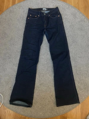 Mörkblå bootcut jeans XS från 157 - Säljer ett par mörkblå jeans från 157 i storlek XS med full längd. Klassisk femficksmodell med snygga kontrastsömmar och bootcut-ben. Jeansen har knappar och nitar i silverfärg samt bakfickor med lock och knapp. Perfekta till sneakers eller boots.