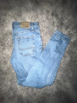 Ljusblå Garcia dad fit jeans strl 164 - Säljer ett par ljusblå Garcia jeans i modellen Dalino Dad Fit med relaxed waist och tapered leg. Klassisk femficksdesign, snygga kontrastsömmar och skön passform. Perfekta för dig som gillar en avslappnad men ändå stilren look.