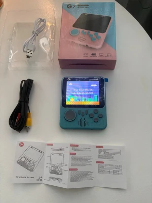 G7 Game Box Handhållen Spelkonsol ca 600 spel  - Portabel G7 Game Box med med ca 600 spell 3,5" färgskärm. Slimmad och trendig design, stöd för flera plattformar och kan anslutas till TV. Levereras med laddkabel, AV-kabel och manual. Konsolen är i mycket fint skick, inga synliga defekter.
