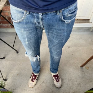 Dondup george - Säljer ett par blå jeans från Dondup george med snygga slitningar och hål på ena knät. Passformen är george och storleken är 33 men skulle säga att den sitter som 32 eller 31. Lagat hål! (Se bilder)  Pris kan disskuteras vid snabbt köp. 