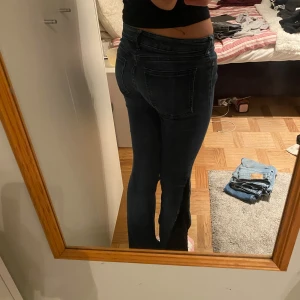 Mörkblå bootcut jeans - Säljer ett par mörkblå jeans med bootcut-modell och låg midja. Jeansen är omdtdds och har en unik design med svart tyg på sidorna🥰