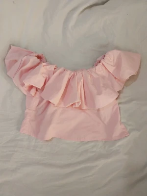 Ljusrosa offshoulder topp från Amisu - Säljer en ljusrosa  kort topp med volang från Amisu i storlek S köpt på New Yorker. Snvänd gåtal gånger, inköpt i somras. Katt finns I hemmet.