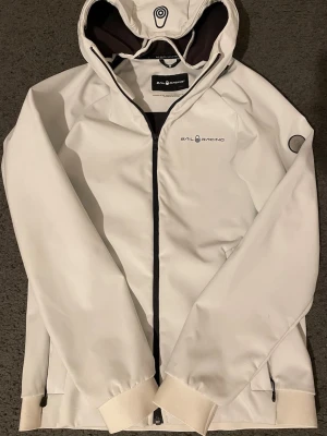 Sail Racing Vindjacka - Perfekt vindjacka för höst/vår från Sail Racing. Varm och bekväm. Finns två svarta fläckor vid framsidan (se bild 3). Har ej försökt tvätta den så noggrant, sänker priset pga fläcken. 