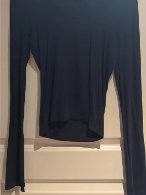 Mörkblå långärmad topp Gina Tricot - En stilren mörkblå långärmad topp från Gina Tricot i storlek S. Toppen har en enkel och clean design med rund hals och smal passform. Perfekt att matcha med jeans eller kjol för en snygg look.