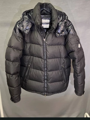 Moncler jacka - Hej! Säljer denna sjukt feta moncler jacka! Size 4 sitter som M. Modellen är 180. Jackan passar 182-190cm bäst! Skick 6/10 de finns flera defekter, så som cartoon tag lossnat, dragkedja fästet borta (men funkar fortfarande) men har mycket liv kvar! Den har inte några hål som läcker dun.  Riktigt fet jacka för detta pris! Det är en älldre modell. Garanterar äktehet! Hör av dig vid minsta fundering ! ☺️