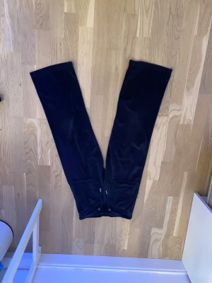 Svarta mjukisbyxor från 157 - Mörka svarta mjukisbyxor från 157 med dragsko i midjan. Byxorna har raka ben och är tillverkade i ett mjukt, fleeceliknande material som känns riktigt skönt mot huden. Perfekta för chill dagar eller när du vill vara extra bekväm.