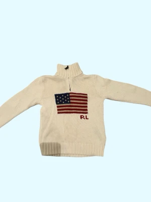Vit stickad tröja Polo Ralph Lauren - Säljer en vit stickad tröja från Polo Ralph Lauren med amerikansk flagga på bröstet och RL-broderi. Tröjan har hög krage, half zip-dragkedja och långa ärmar. Perfekt för dig som gillar klassisk preppy stil.