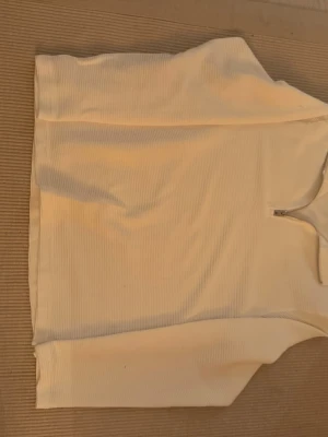 Vit ribbad half zip-tröja H&M - Vit långärmad tröja från H&M i ribbad bomullsmix. Tröjan har en hög krage med half zip-dragkedja och regular fit. Perfekt för lager-på-lager och enkel att styla till olika outfits.