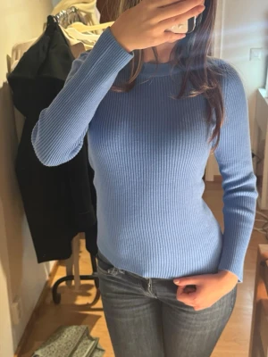 Ljusblå ribbad stickad tröja - Supersnygg ljusblå stickad tröja med ribbad struktur och lång ärm. Helt ny!