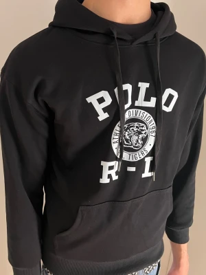 Ralph Lauren hoodie - Svart ralph lauren hoodie med tryck. Hoodien är i mycket bra skick knappt använd. Kan gå ner i pris vid snabb affär!