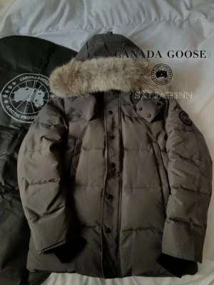 Går Canada Goose WyndHam Parka Black Label - 🩶 Canada Goose Wyndham Parka – Grå (Black Label), strl S 🩶  Stilren och eftertraktad Wyndham Parka i elegant grå färg. En mycket varm och funktionell vinterjacka med högkvalitativ dunfyllning och modern passform. Utrustad med justerbar huva med äkta pälskrage, slitstarkt yttertyg och diskret svart Canada Goose-patch på armen (Black Label). Perfekt för nordiskt vinterklimat.   📦 Snabb leverans – skickas samma dag (om ej hindr.) 📩 Kontakta mig gärna vid frågor!