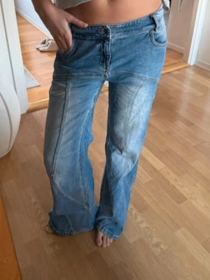 Lågmidjade blå wide jeans - Ljusblå jeans med coola detaljer. Midja 82 innerben 84.