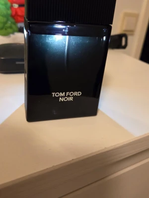 Tom Ford Noir EdP 100ml - Tom Ford Noir Eau de Parfum, 100 ml. En elegant och stilren doft i svart flaska, tillverkad i Schweiz. Perfekt för dig som vill sticka ut med en exklusiv touch.obs ,har inte sparat förpackningen,så att kommer utan förpackning,så som du ser på bilderna obs flaskan har lite repor det kan man se på bilden,ca 90 ml.kvar i flaskan,det ser du på en av bilderna,säljer biligt pga. Saknar förpackningen och flaskan är lite repig