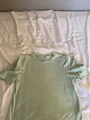 Ljusgrön t-shirt från Aware - Säljer en ljusgrön t-shirt från Aware by Vero Moda i storlek S. T-shirten har puffiga korta ärmar och rund halsringning. Tillverkad i mjuk bomull . Perfekt för dig som gillar en enkel men ändå söt look.