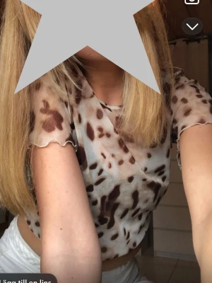 Leopardmönstrad mesh topp från KappAhl - Säljer en leopardmönstrad mesh topp från KappAhl. Toppen är transparent, croppad och har korta ärmar med vågig kant. Färgerna går i beige och brunt. Det beiga linnet följer med.