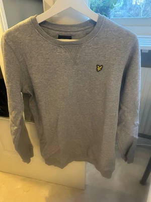 Grå sweatshirt från Lyle & Scott - En stilren grå sweatshirt från Lyle & Scott. Den är 14-15 år vilket motsvarar ungefär S. Skicket på den är mycket bra och den är inte använd så mycket. Nypris runt 650, mitt pris är 400! 