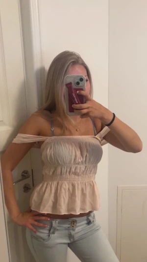 Ljusrosa topp  - Supersöt ljusrosa blus/topp med smockad midja. Toppen har volang nertill och är tillverkad i ett tunt, luftigt bomullstyg. Man kan välja hur man vill ha banden, antingen offshoulder eller inte🩷🩷