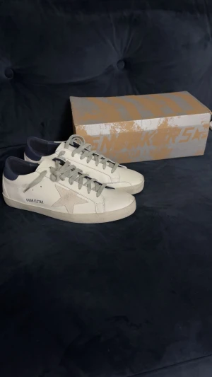 Vita Golden Goose Skor - Säljer ett par vita Golden goose skor. Skorna är i nyskick och är i storlek 42. Klassisk och stilren design som funkar till allt. Om ni vill ha fler bilder eller om ni undrar något är det bara att säga till. Tar även emot byten💯🤗