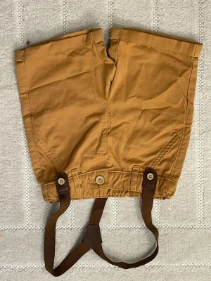 Bruna shorts med hängslen LC Waikiki - Säljer ett par bruna shorts från LC Waikiki med coola hängslen och knappar framtill. Shortsen har elastisk midja och är gjorda i mjuk bomull, perfekta för en chill och avslappnad stil. Passar barn mellan 80-86 cm.